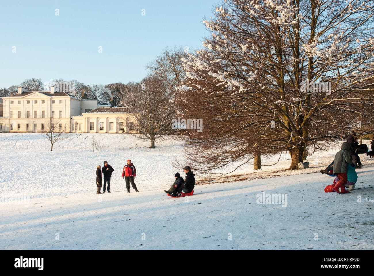 On a snowy winters day families sledge down slopes in front of Kenwood House, Hampstead, UK. Stock Photo
