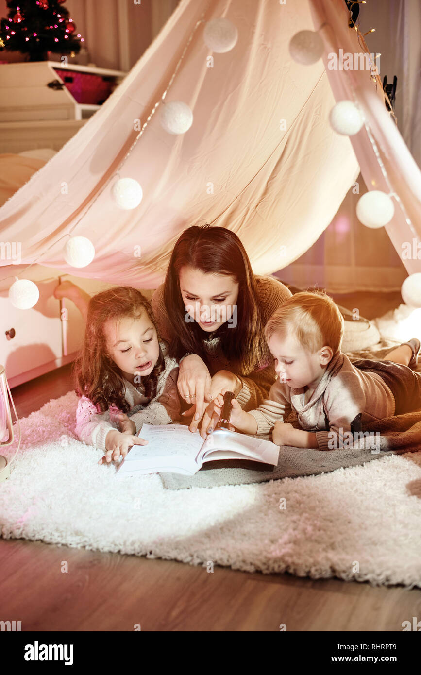 Young mother reading a novel with her children Stock Photo