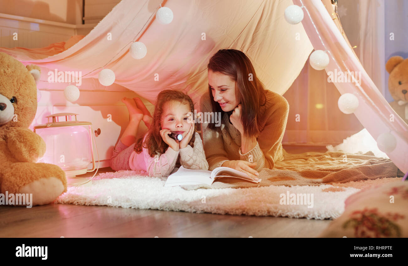 Happy mother reading a novel with her daughter Stock Photo