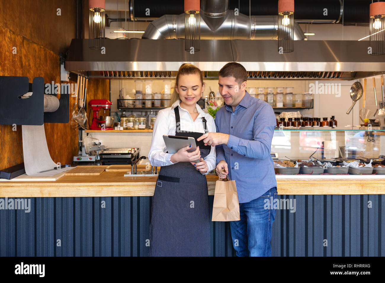 Small business owner couple in little family restaurant looking at tablet for online orders – concept of family business with young entrepreneurs Stock Photo