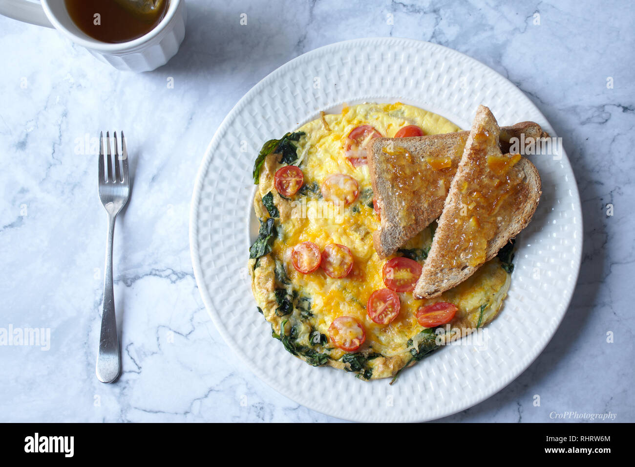 Spanish Omelet with cherry tomatoes along with cup of tea, toast and