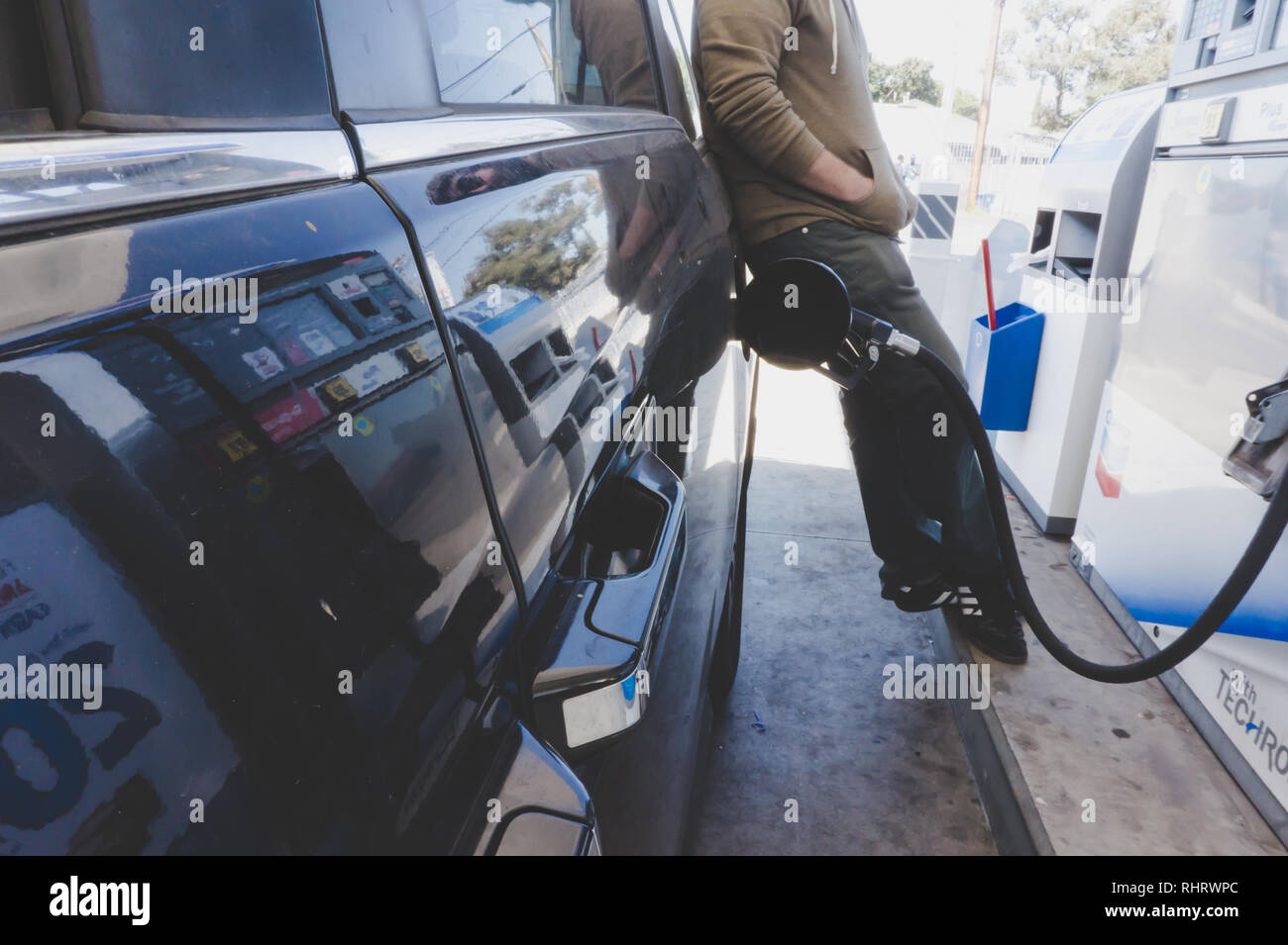 Man pumping fuel into his vehicle while watching the price display at