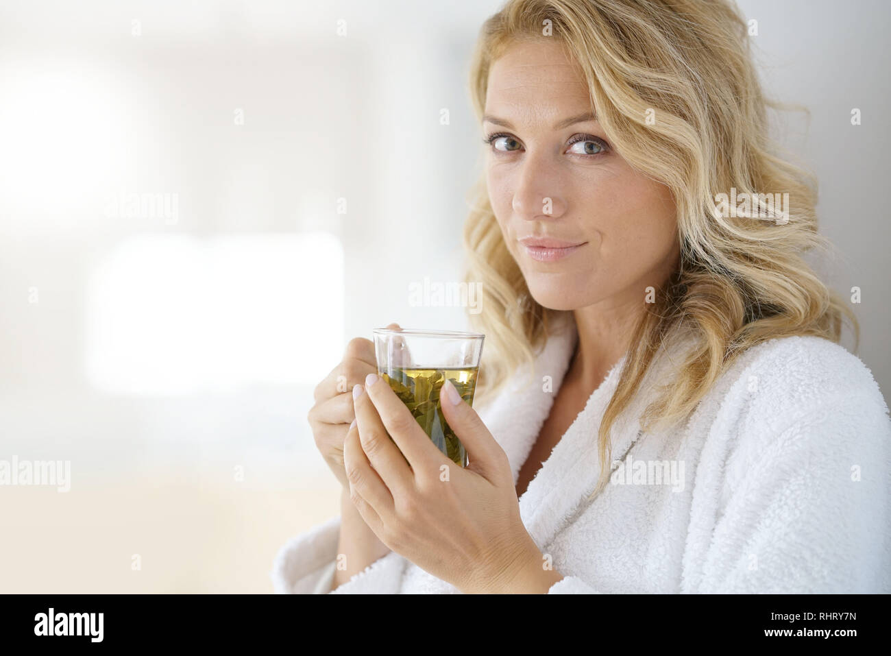 Portrait of attractive 40yearold woman in bathrobe drinking infusion