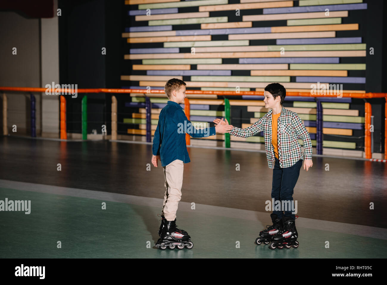 Pretty smiling children in roller skates stretching arms to each other