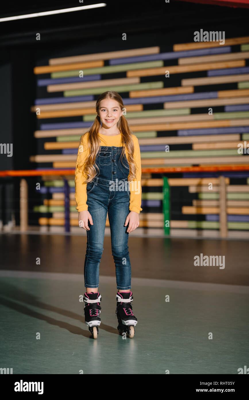 Pretty smiling child in roller skate standing in spacious roller rink