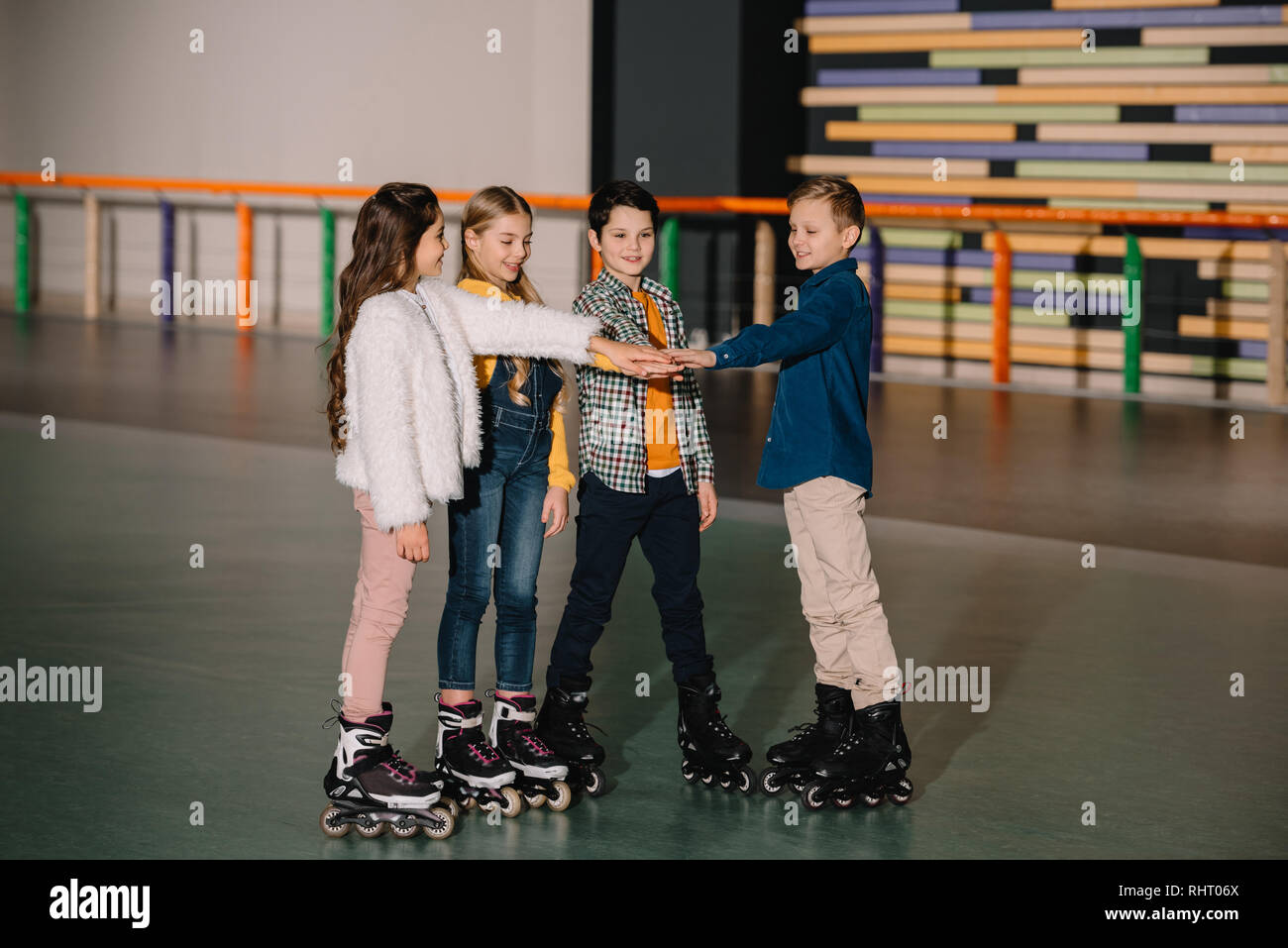 Smiling children in roller skates staying on roller rink and stretching