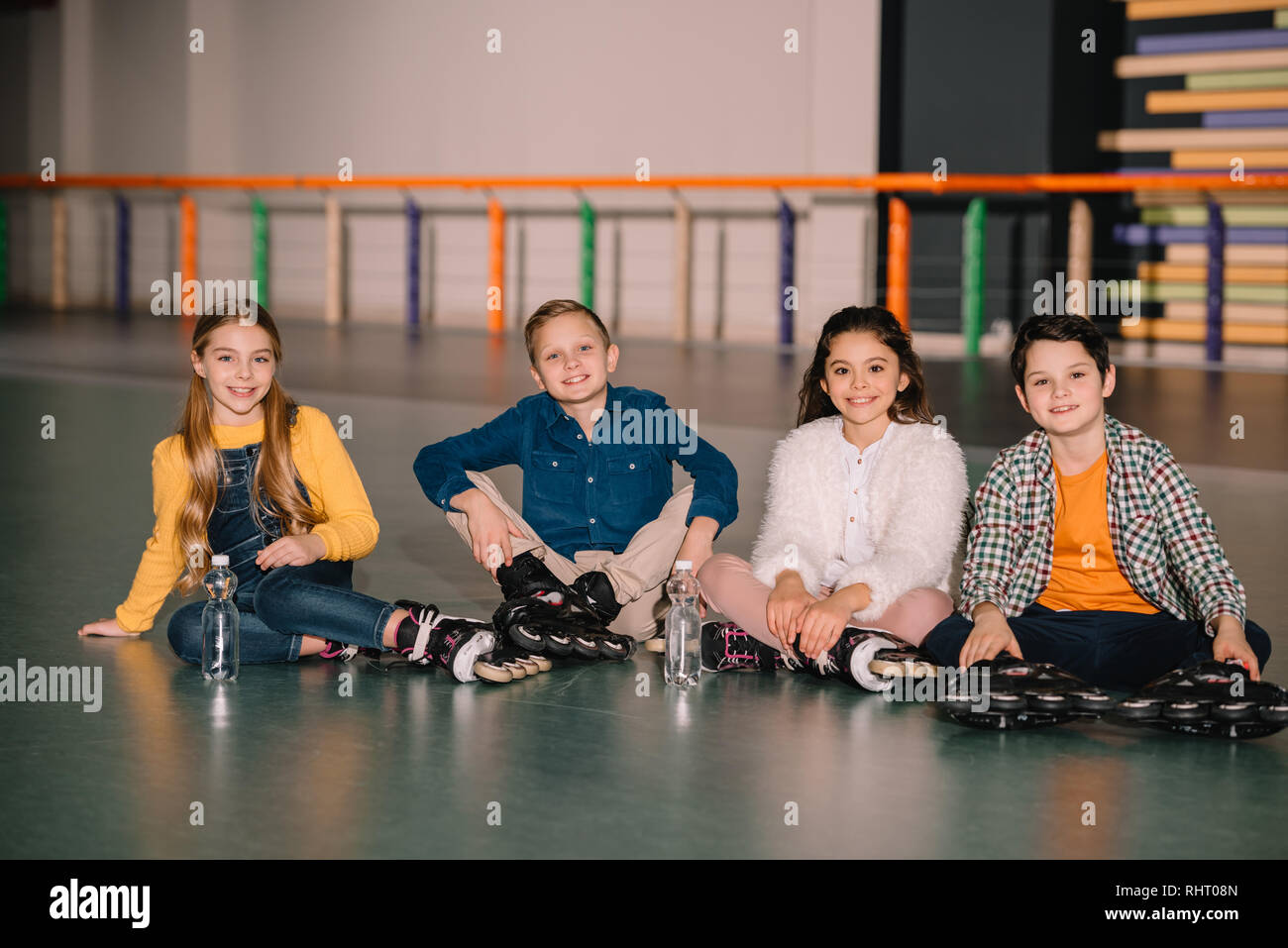 Cheerful kids in roller skates sitting on ground Stock Photo