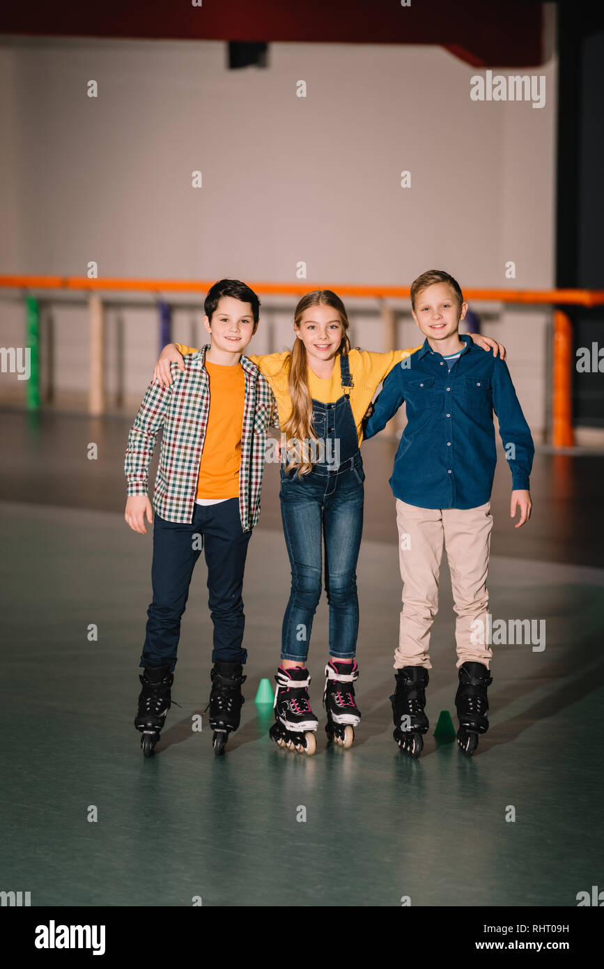 Full length shot of smiling kids hugs on skating rink Stock Photo