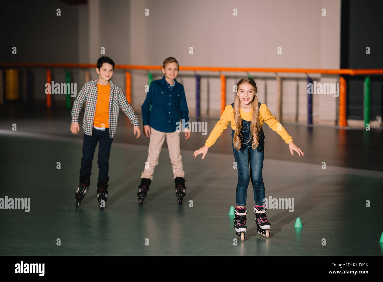 Smiling kids in roller skates training on rink Stock Photo
