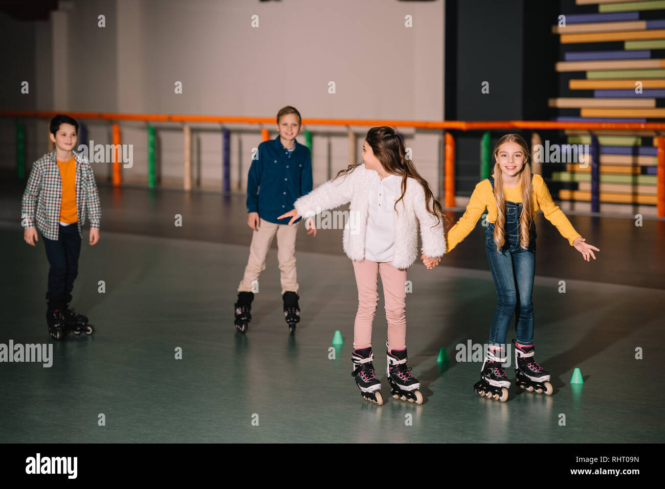 Friends in roller skaters laughing and holding hands Stock Photo