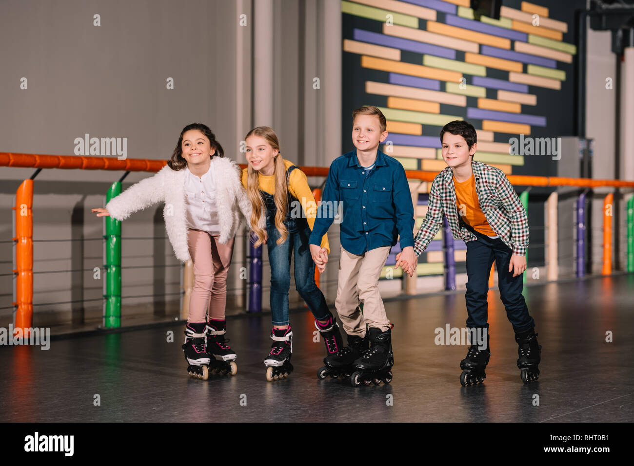 Four smiling kids holding hands while skating together Stock Photo