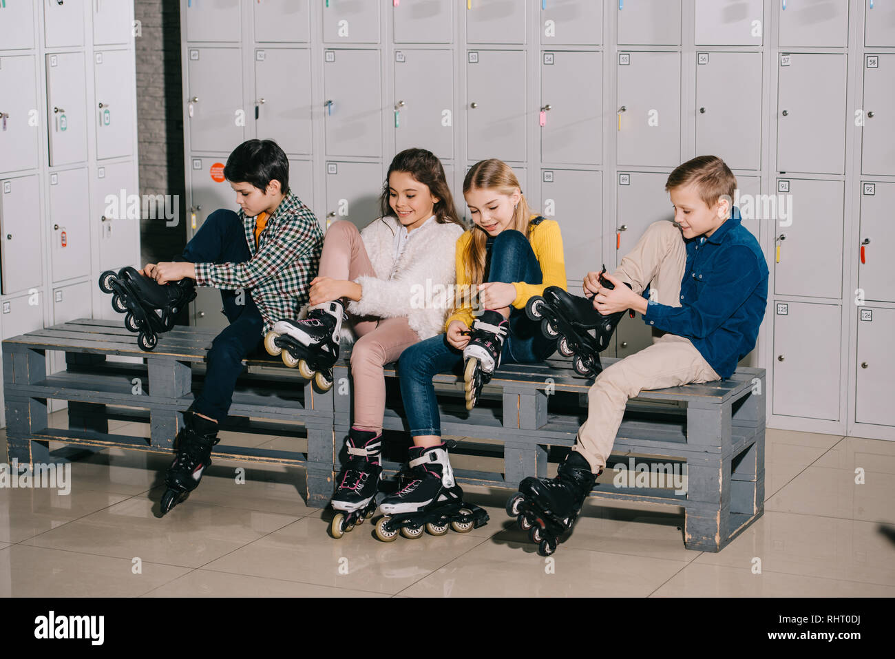 Four smiling kids putting on roller skates Stock Photo