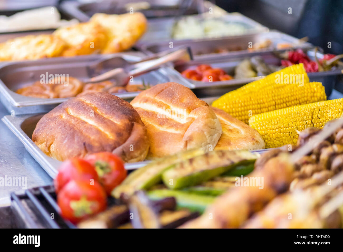 Buns and boiled corn on the counter of the store with a blurred ...