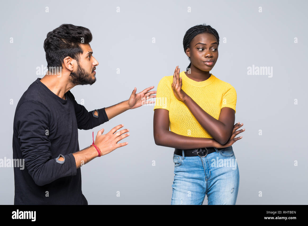 Portrait of mixed race couple sort out relationships, look in displeasure at each other, have quarrel stand against white background. Interracial fami Stock Photo