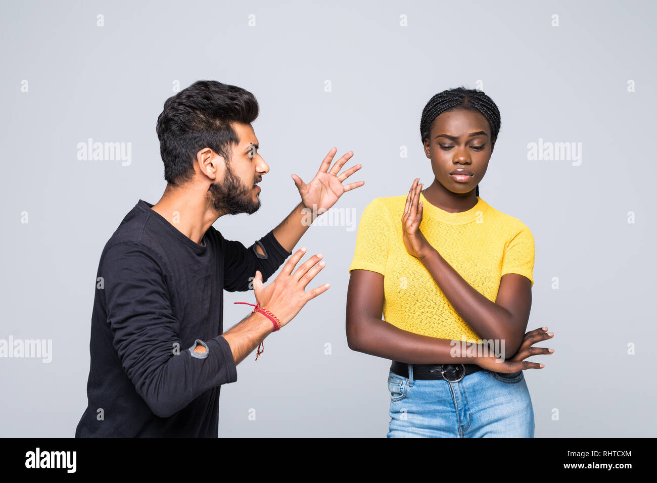 Portrait of mixed race couple sort out relationships, look in displeasure at each other, have quarrel stand against white background. Interracial fami Stock Photo