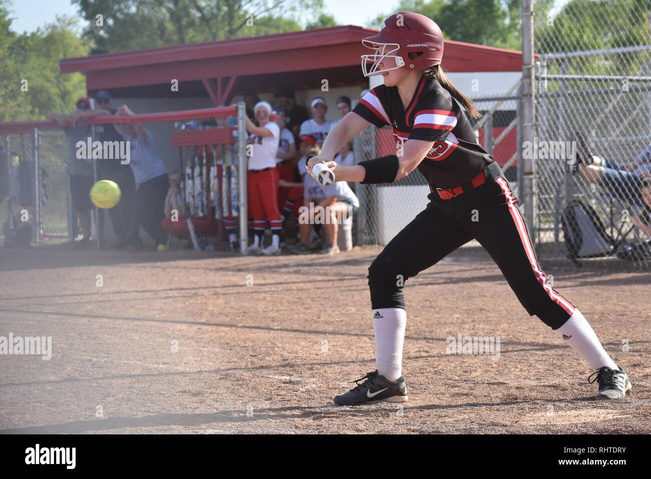 Left-handed high school softball player swings at a pitch Stock Photo