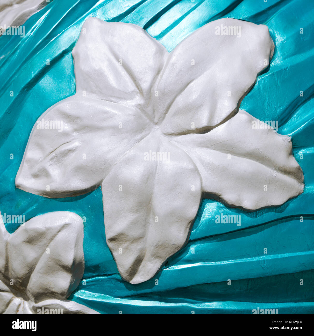 Asian style white orchid flower, sculptured from concrete, surrounded by an aqua colored painted background. It has a square format. Stock Photo
