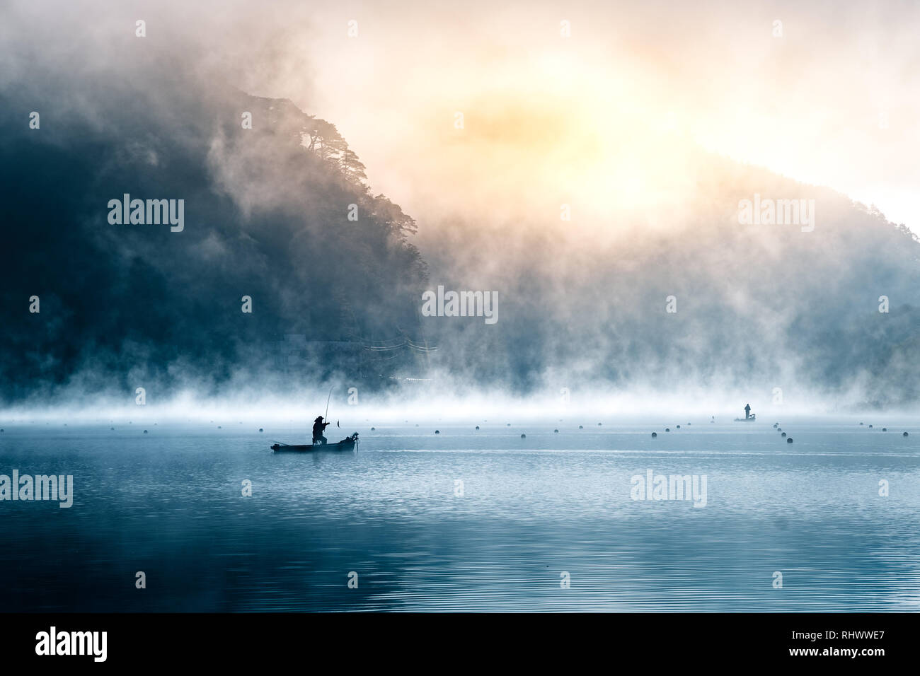 the silhouette of a fisher man with his boat on a misty moring at Lake ...