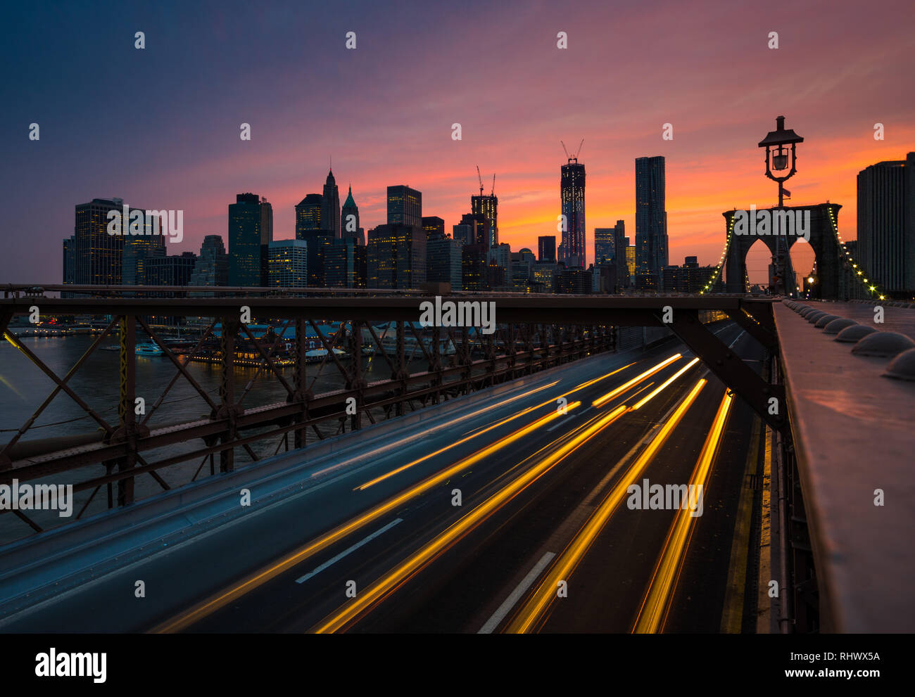 a longexposure capture at Brooklyn Bridge with lighttrails of the passing cars and the world famous silhouette of Manhatten Stock Photo