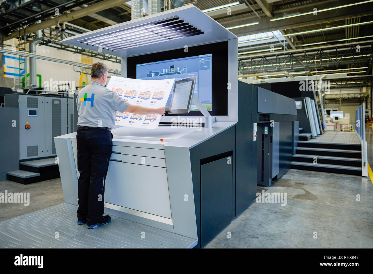 Wiesloch, Germany. 01st Feb, 2019. In a workshop at the headquarters of  Heidelberger Druckmaschinen AG, an employee is holding a printed sheet of  packaging samples in his hands on a "Primefire" digital