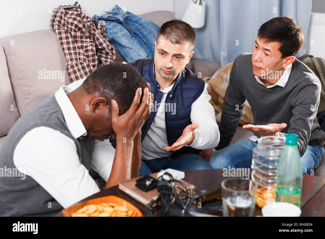 Two men comforting their upset friend while discussing problems at home ...