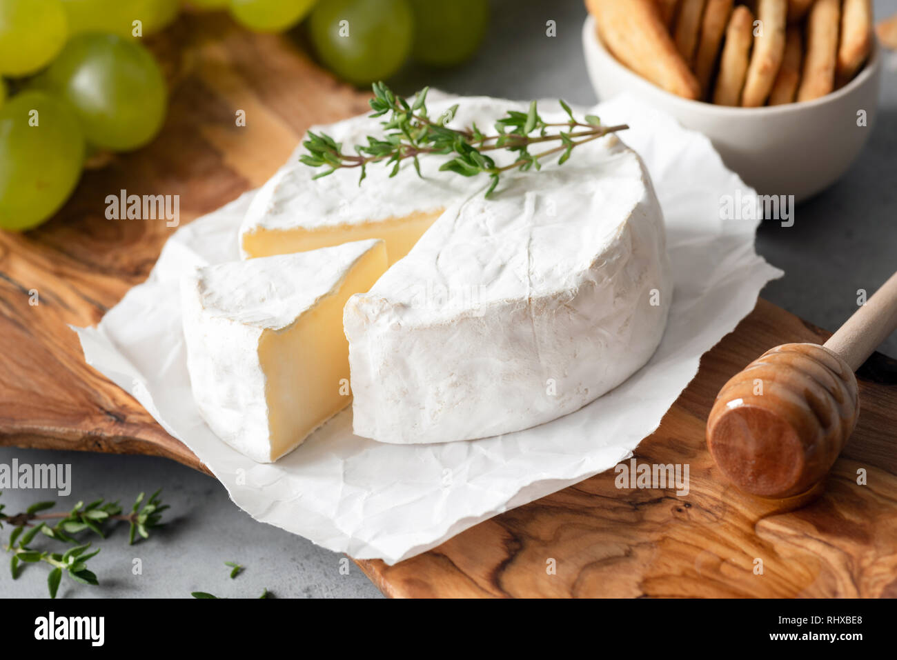 Tasty Brie Cheese or Camembert Cheese On Olive Wooden Serving Board. Closeup view Stock Photo