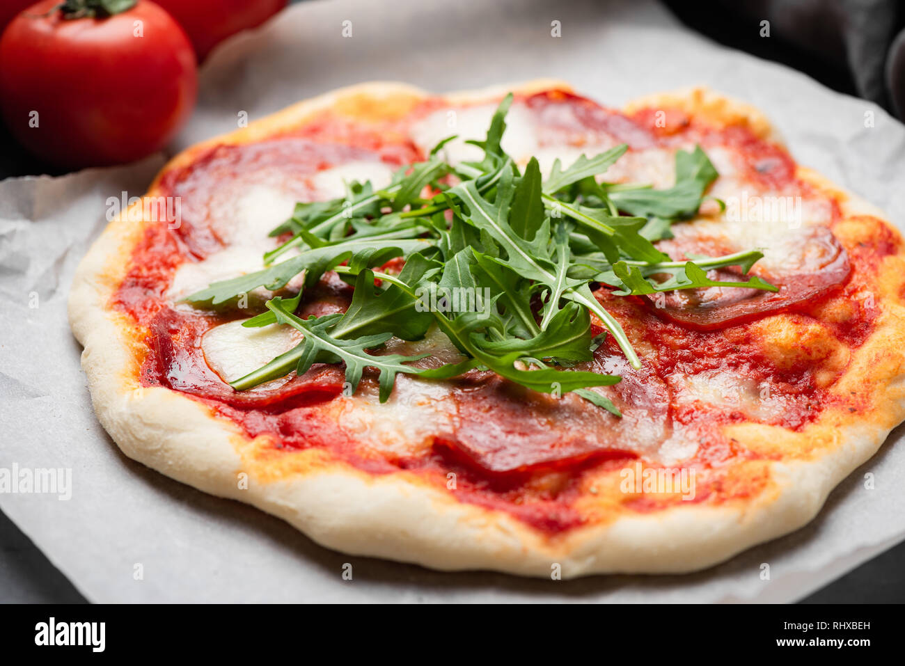 Italian Pizza With Salami And Fresh Arugula. Selective focus. Tasty homemade pizza. Takeout pizza Stock Photo