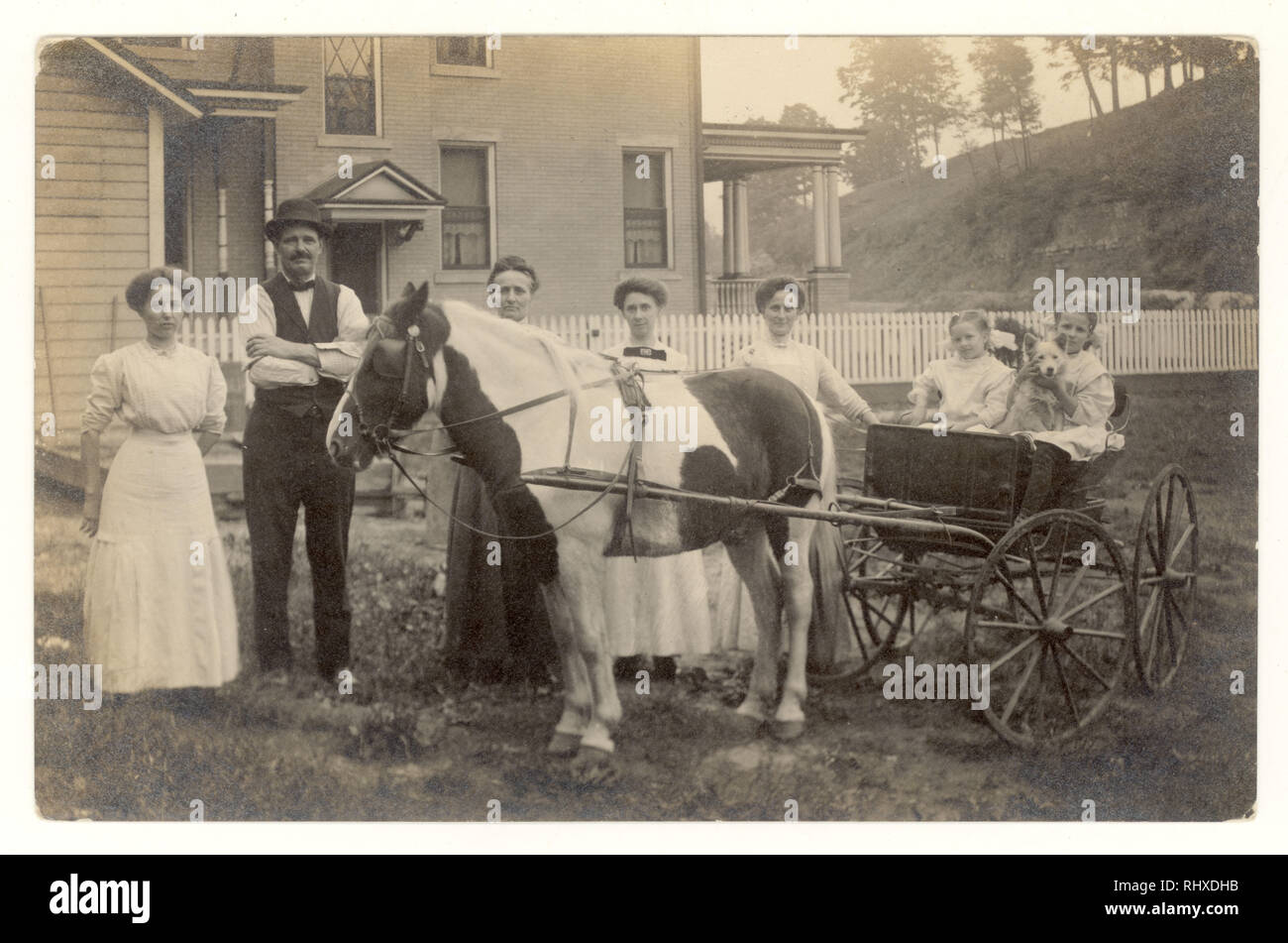 Edwardian postcard of servants posing outside newly-built grand house with the children, little girls, of the house sitting in a pony and trap, USA, circa 1910, 1915 Stock Photo