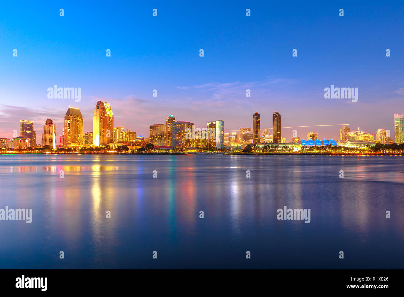 Panoramic landscape of San Diego skyline with illuminated skyscrapers reflecting in San Diego Bay at twilight. Districts of Waterfront Marina skyline Stock Photo