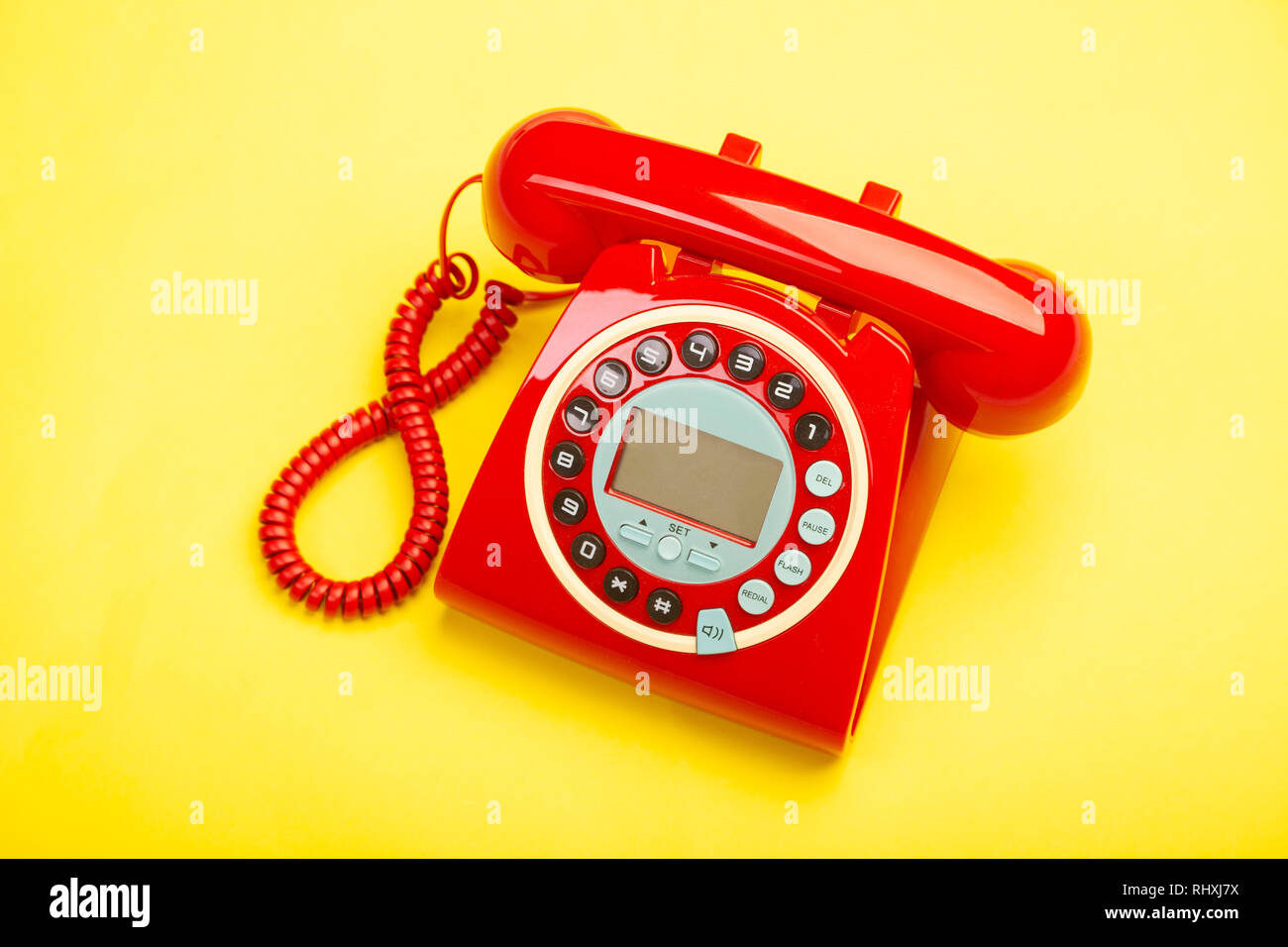 A red retro telephone from above against a yellow background. Stock Photo