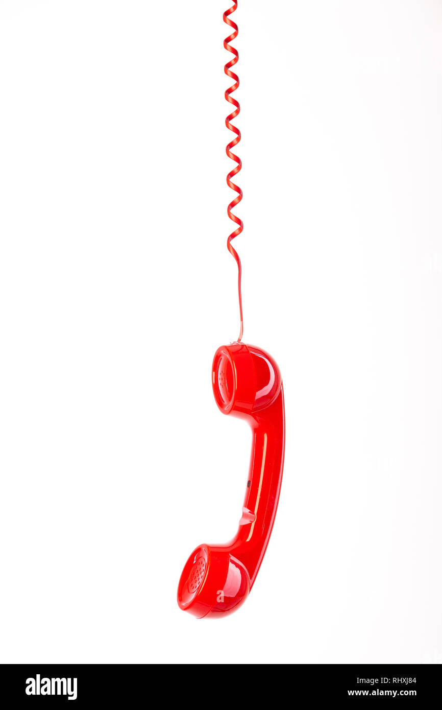 A red telephone handset hanging from it's cord. Stock Photo