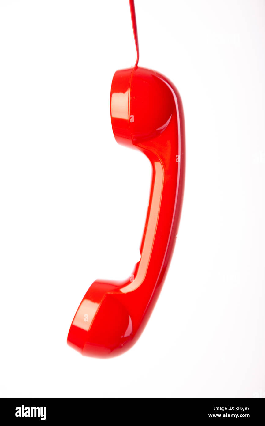 A red telephone handset hanging from it's cord. Stock Photo