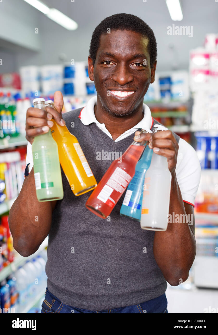 Positive African man choosing energy drinks in supermarket Stock Photo