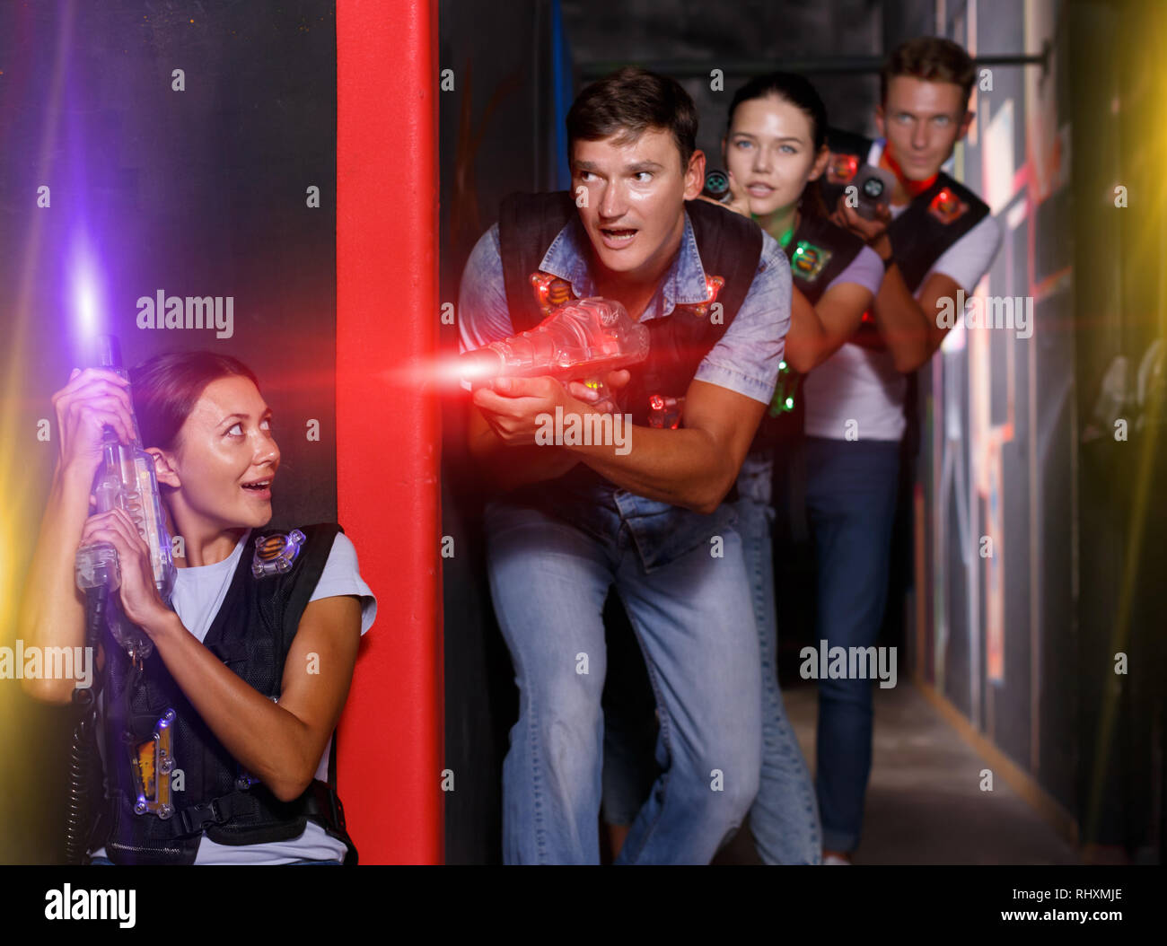 Young girl with laser guns took aim and having fun with friends during laser tag game Stock