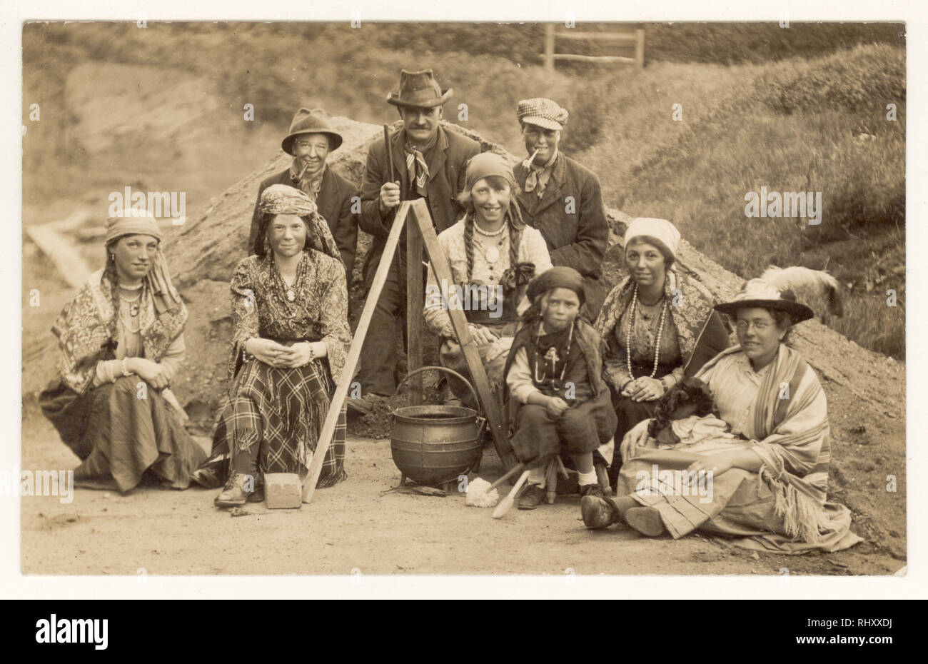 Early 1900's postcard of family dressed as gypsies in traditional dress, blackened faces, stitting next to cooking pot, posing for a group photograph,  U.K. circa 1920's Stock Photo