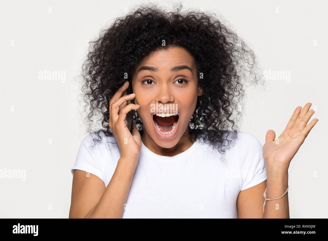 Excited overjoyed african girl hearing great news talking on phone Stock Photo