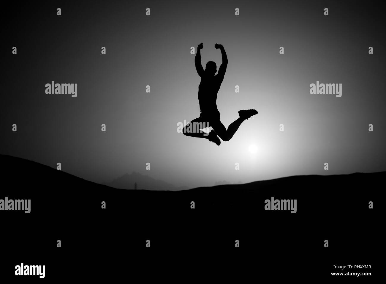 Sport, fitness activity. Silhouette of sportsman. Athlete with muscular body in dusk. Man jump on sunset sky background. Freedom energy concept. he did it Stock Photo