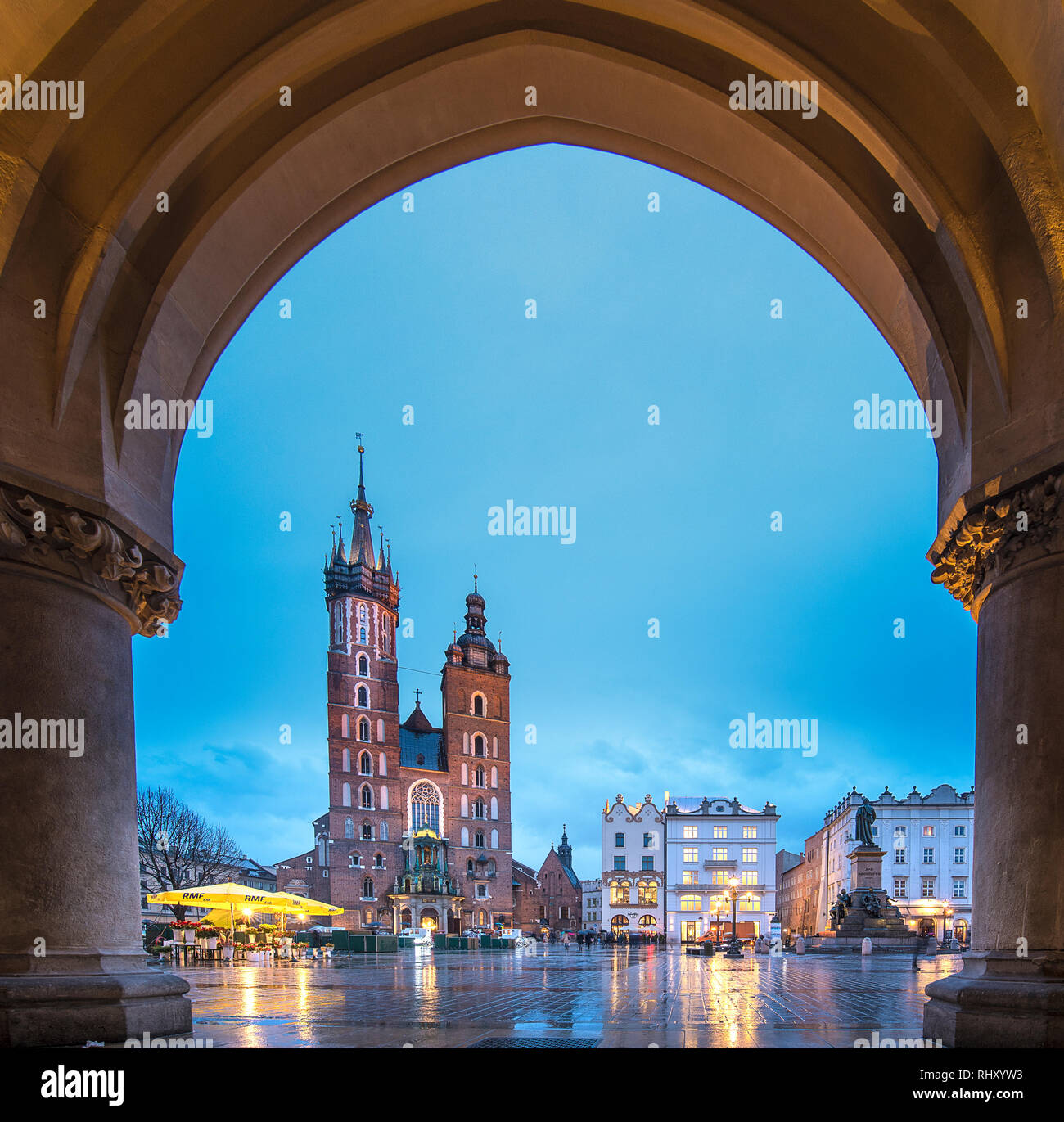 Mary's Basilica (Mariacki Church) and white carriages illuminated on The Main Market Square at night in the Old Town of Krakow (Cracow), Poland Stock Photo