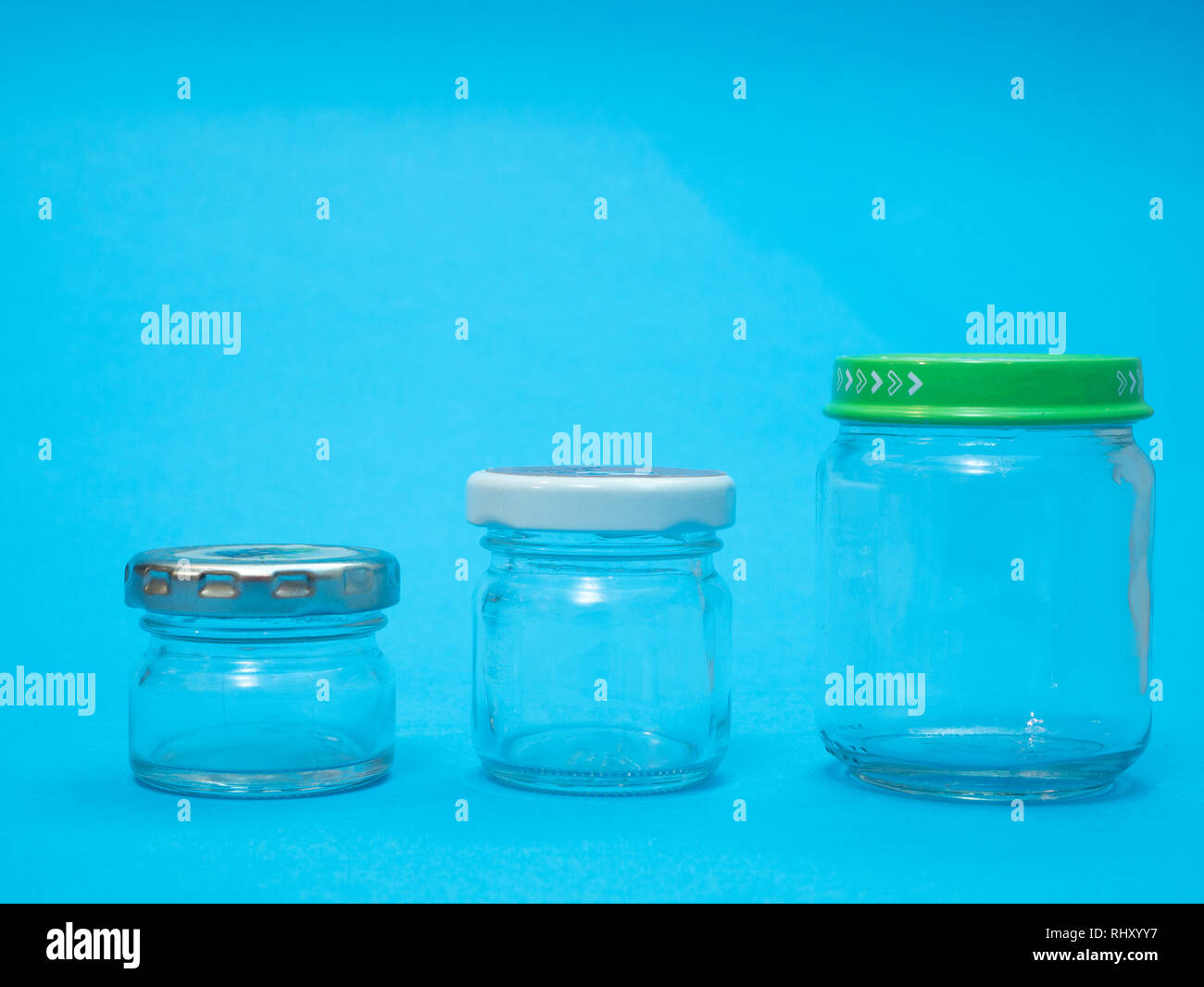 closeup of three glass jars on blue background. different sizes 