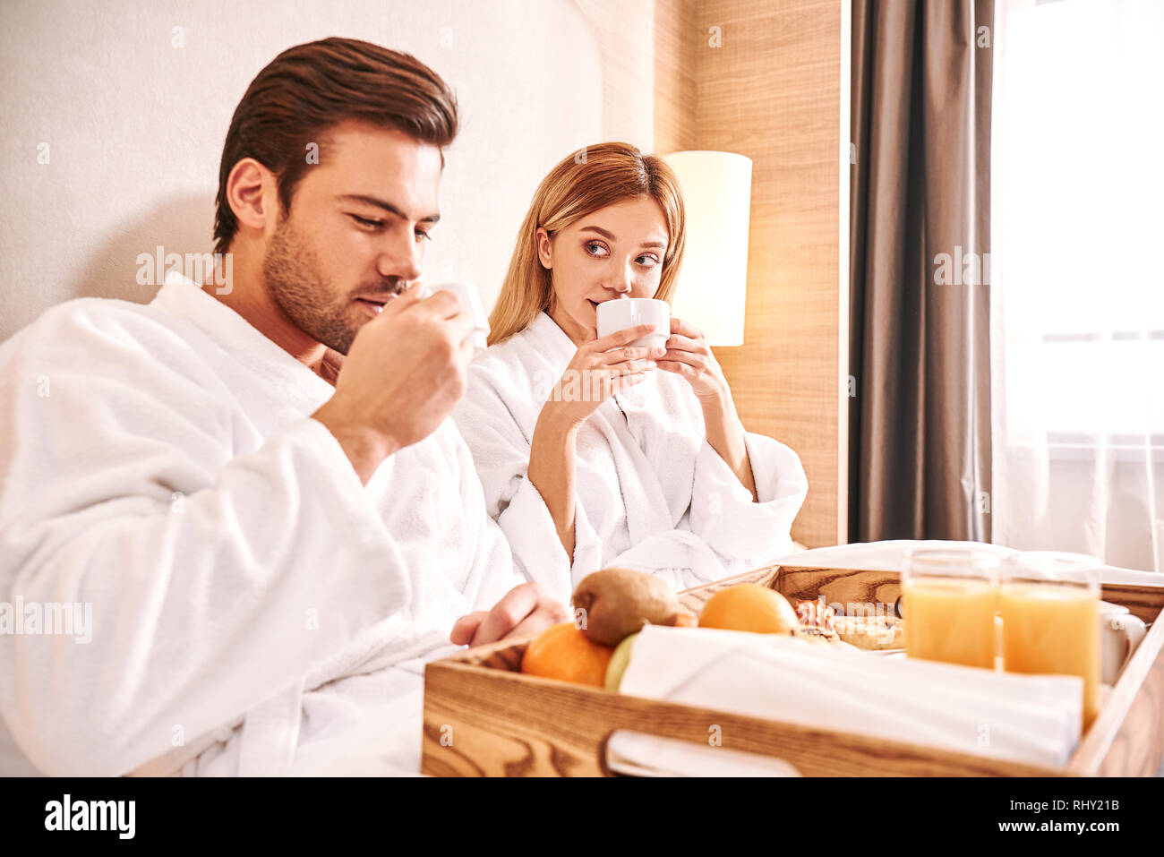 Useful breakfast. Couple are eating in hotel room bed together. Love story. Drinking morning coffee Stock Photo