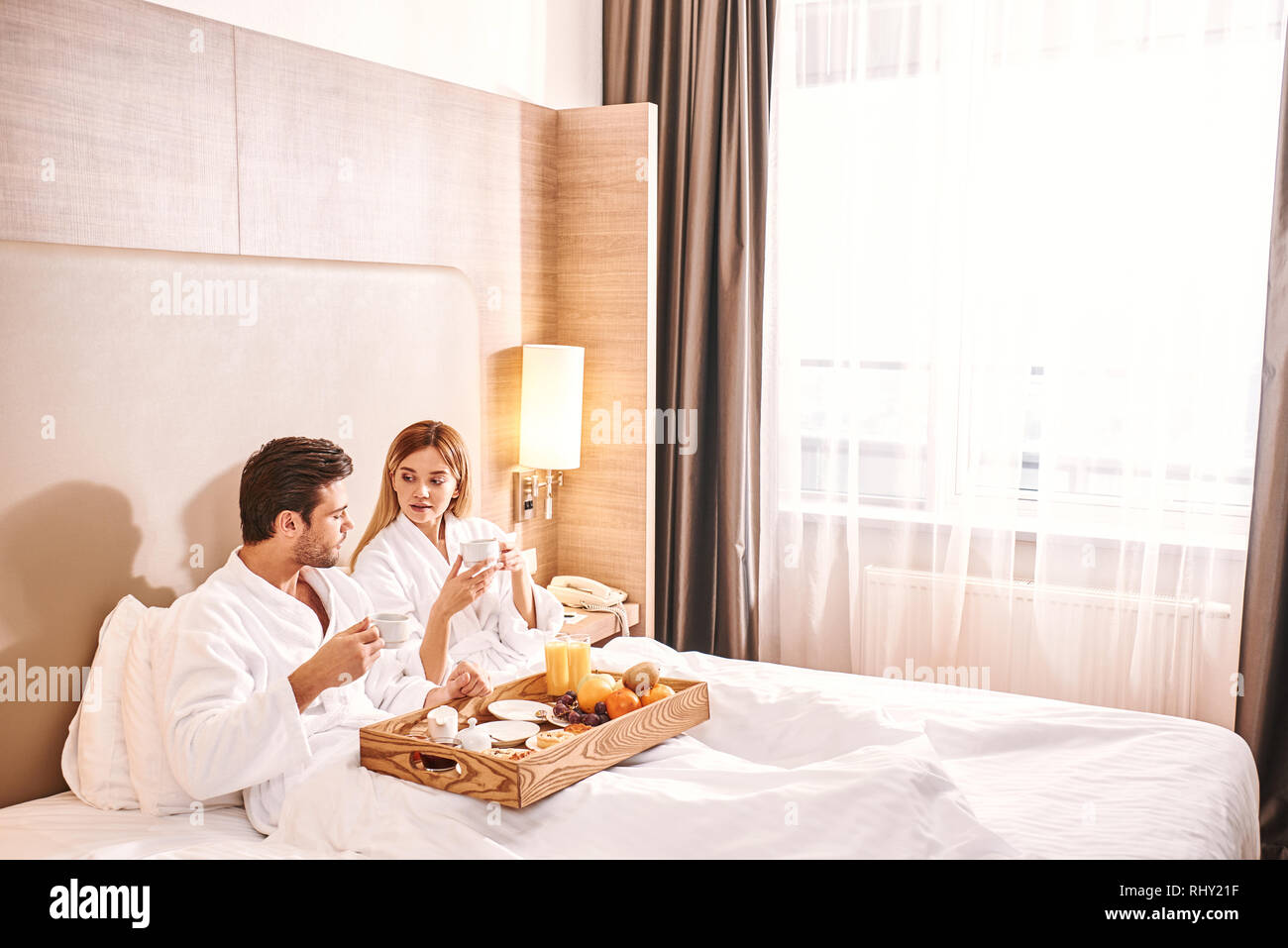 Fresh fruits breakfast. Couple are eating in hotel room bed together. Love story. Stock Photo