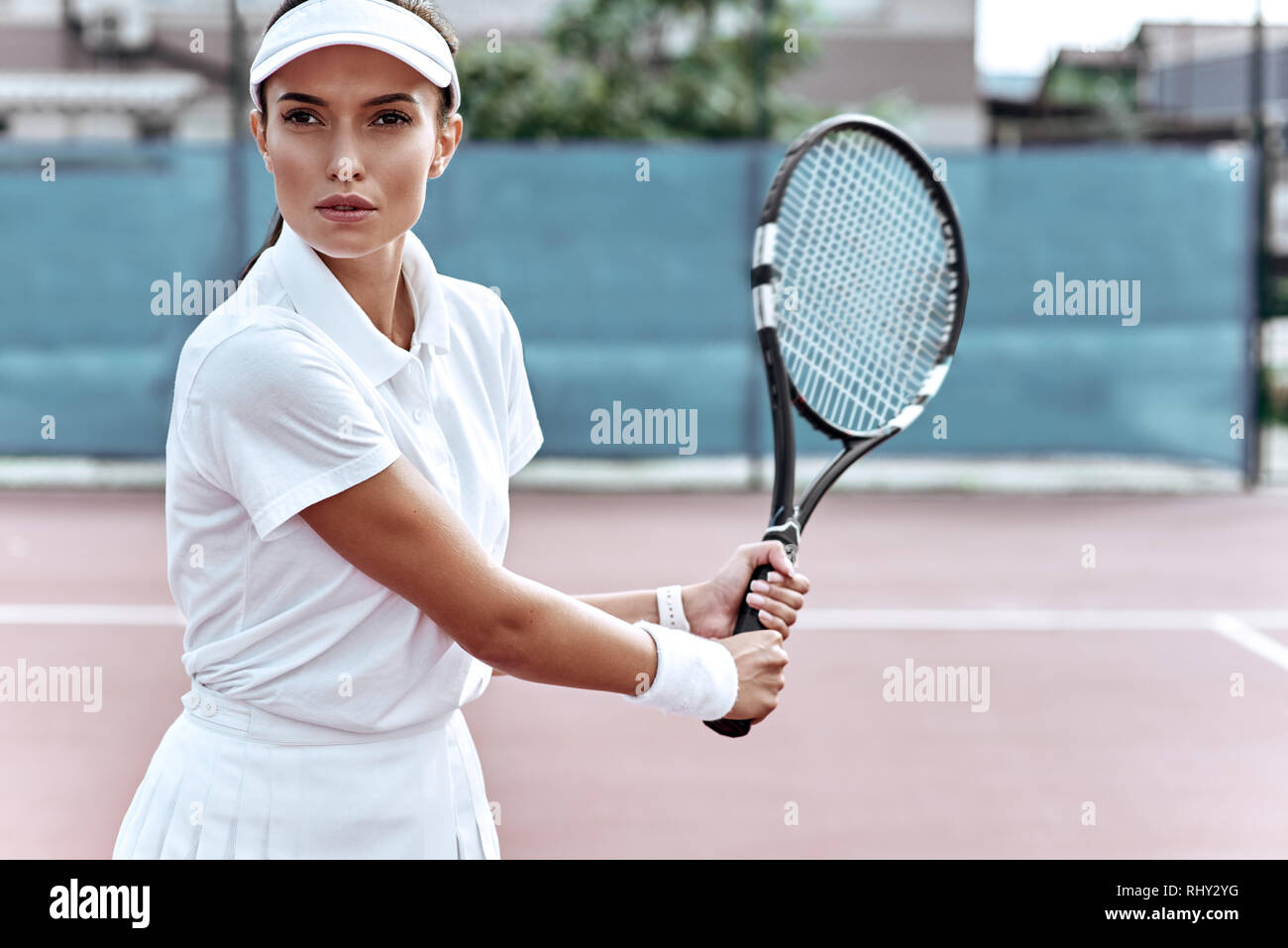 Beautiful woman in white sportswear with a racket in her hand play tennis on the court Stock Photo
