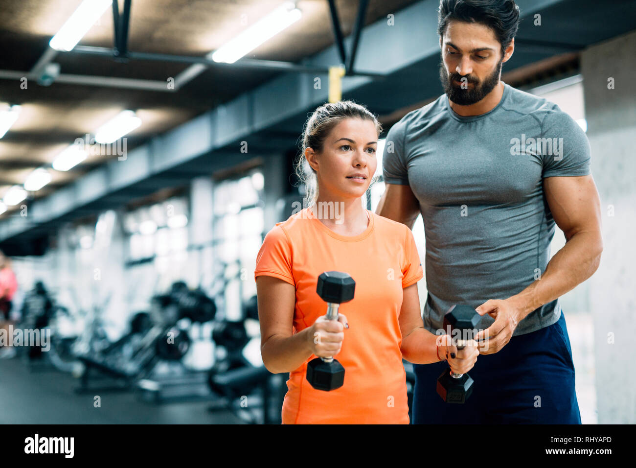 Young beautiful woman doing exercises with personal trainer Stock Photo