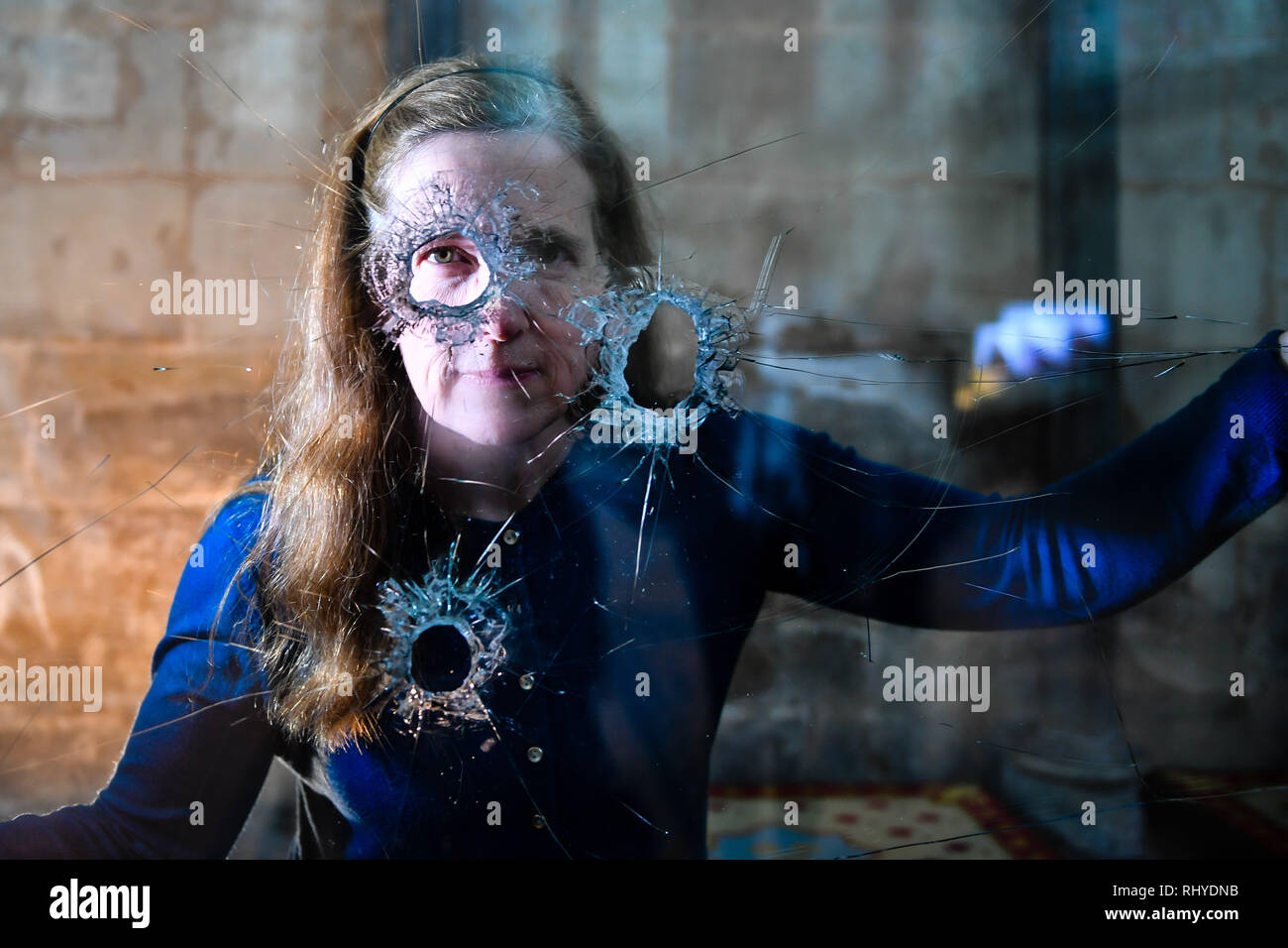 Salisbury Cathedral Archivist Emily Naish looks through holes in reinforced glass that were left after a hammer attack on the casing housing an original Magna Carta inside the medieval Chapter House at the Cathedral, which is now reinstalled for the viewing public. Stock Photo