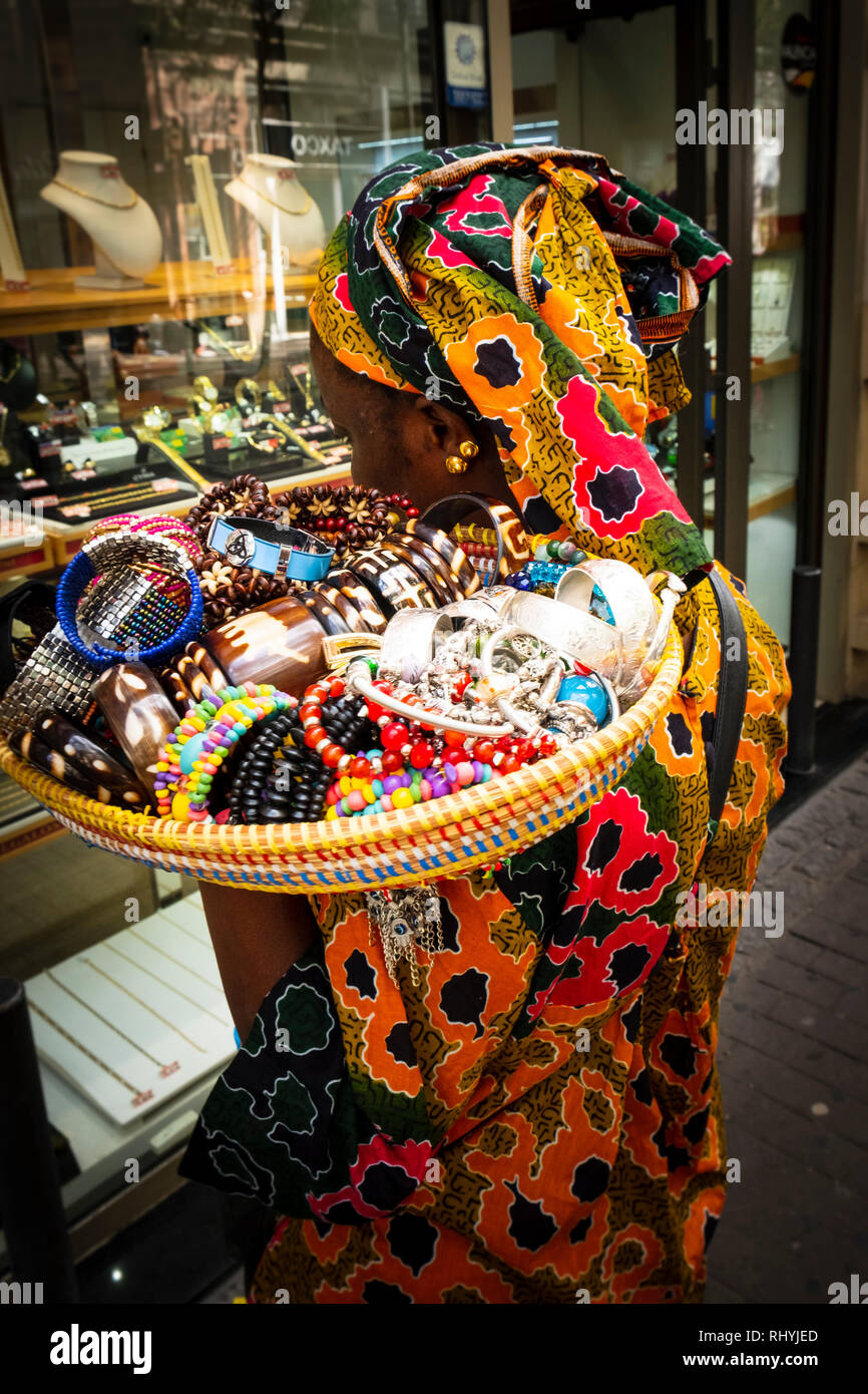 Black woman street seller in traditional dress with basket of trinkets on her shoulder Valencia Spain Stock Photo