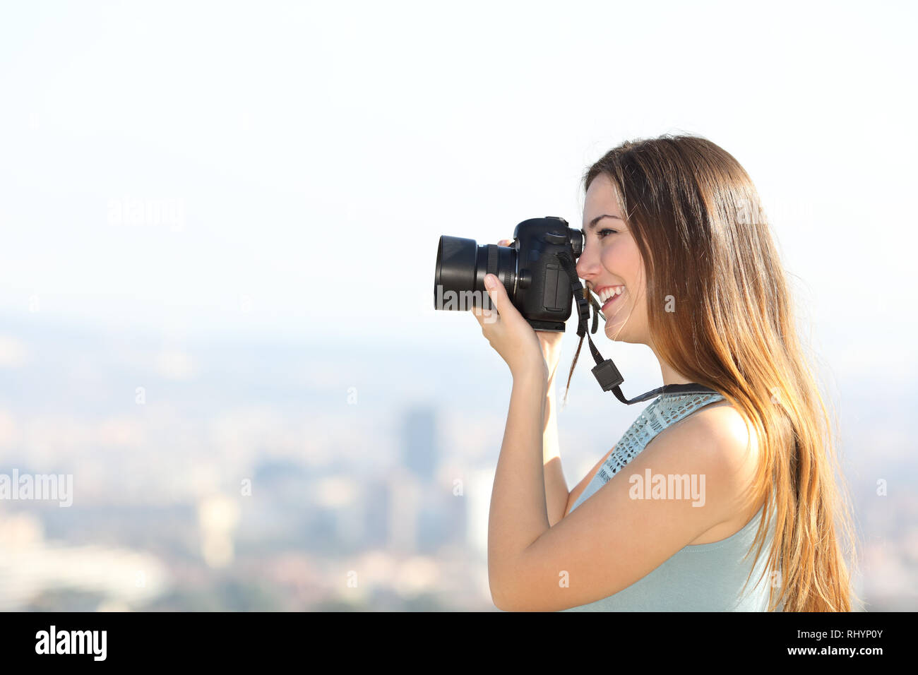 Side view portrait of a happy photographer taking photos with a dslr