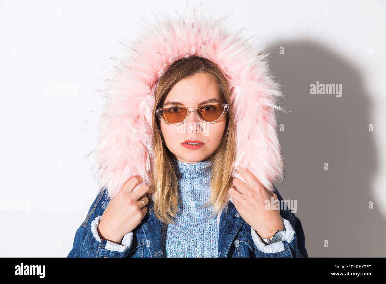 Young fashionable woman in autumn outfit. Denim coat with a hood and pink faux fur Stock Photo
