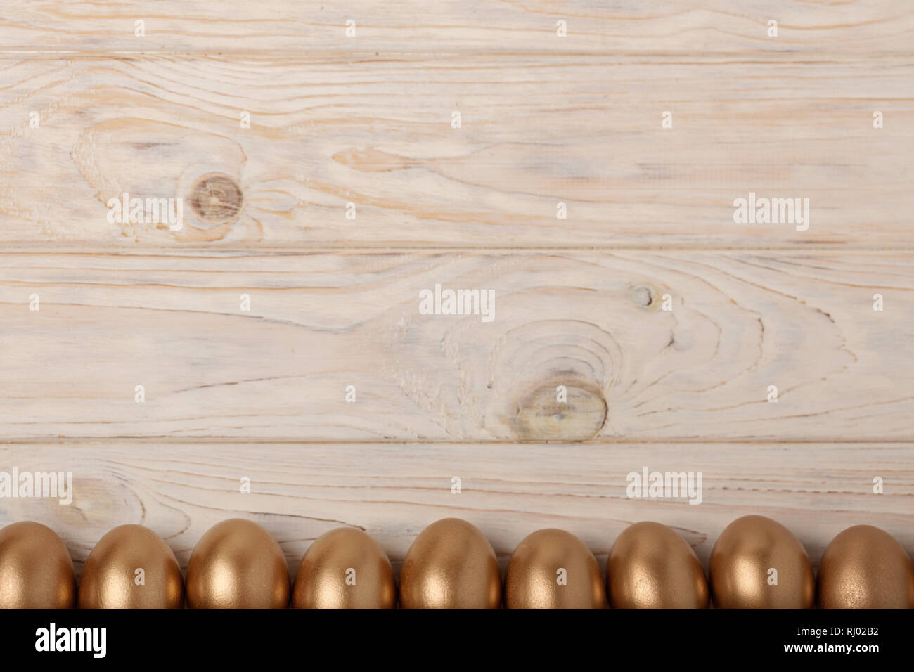 Happy easter! Easter decor and Easter eggs of golden color on a light wooden background. Selective focus. Stock Photo