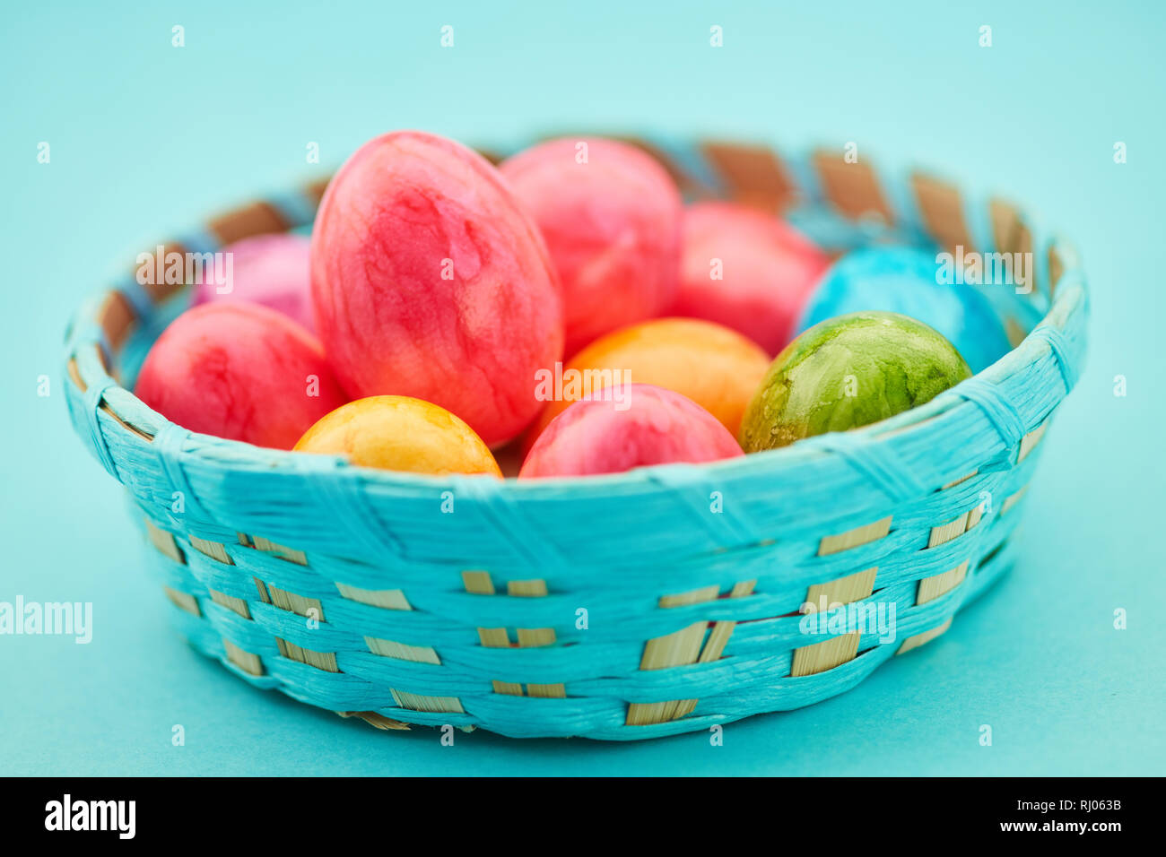 Many colorful Easter eggs lie in a basket at Easter Stock Photo