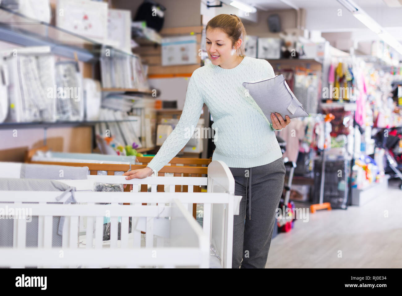 Adult Woman Is Awating For Baby And Choosing Pillow For Crib In